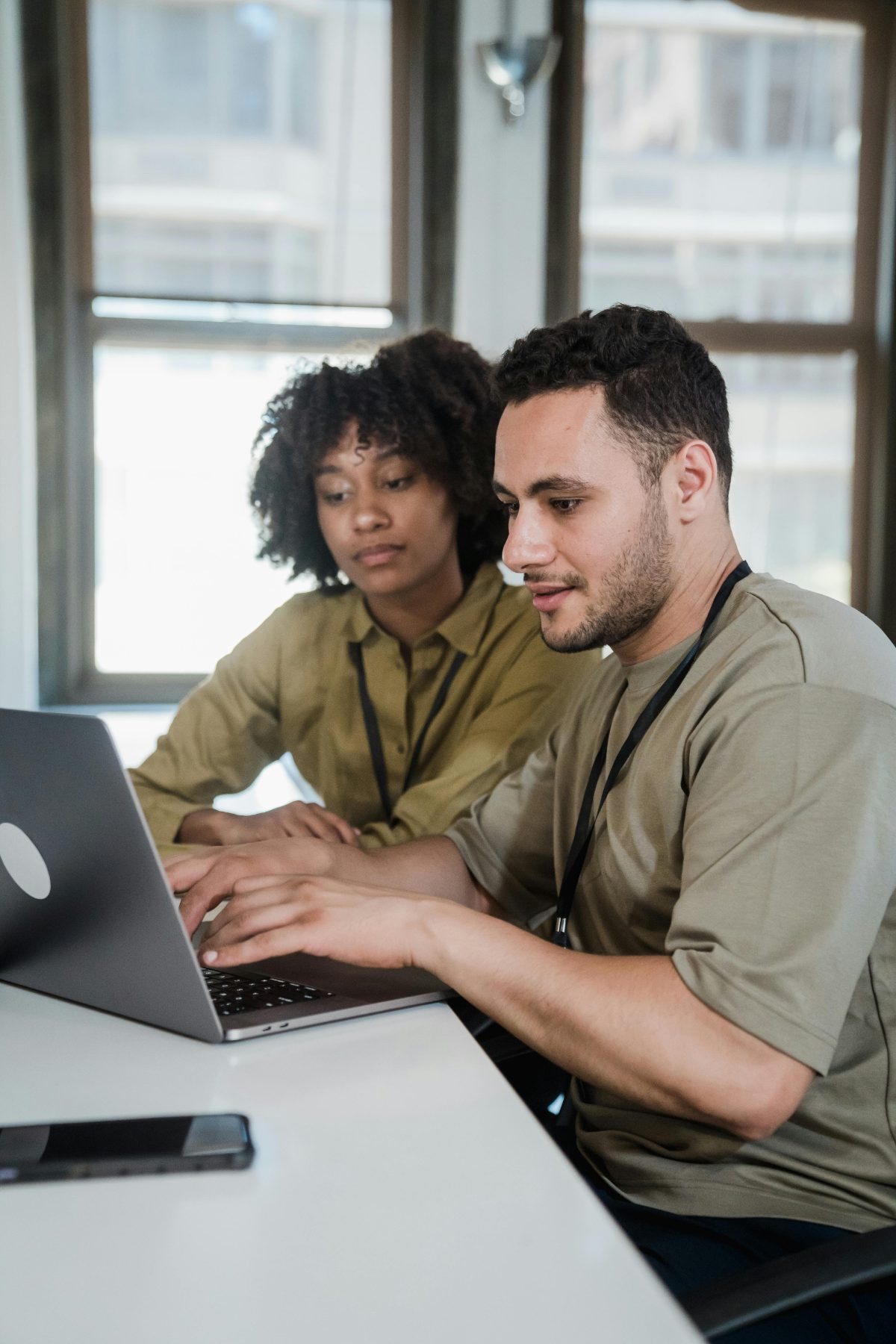 Two colleagues are conferring behind a laptop.