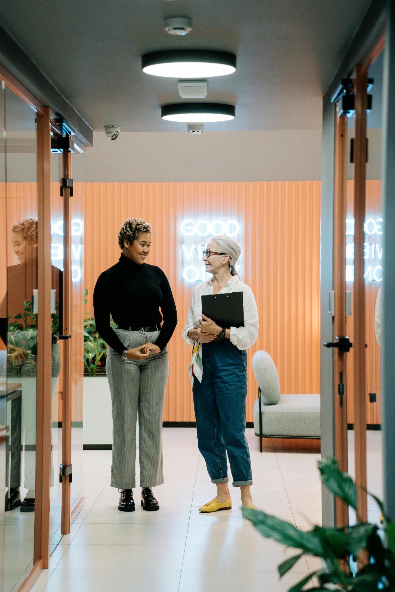 Twee collega's lopen pratend door de gang van het kantoor