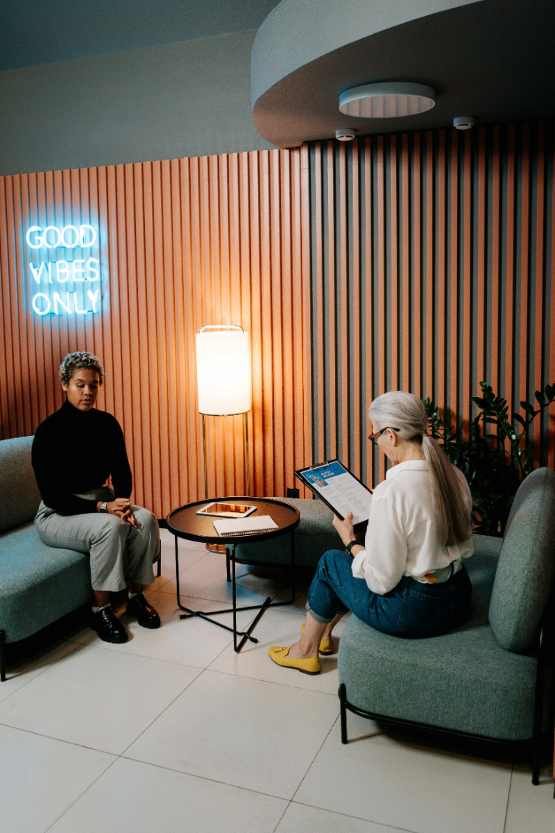 Sollicitatiegesprek in een lounge met "Good vibes only" neonbord op de achtergrond