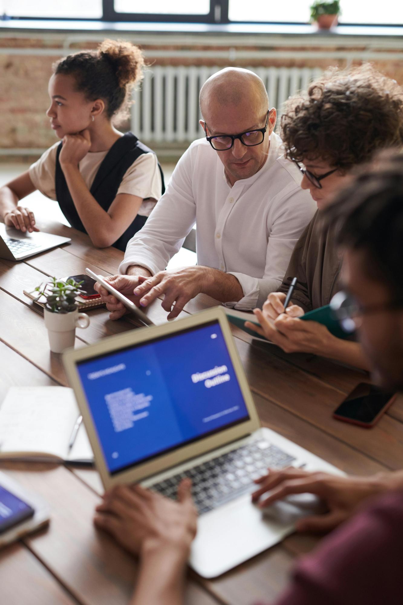 Team bespreekt een presentatie op een laptop tijdens een overleg